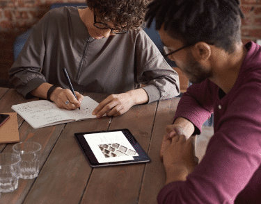 Man wearing purple long sleeved shirt looking at iPad